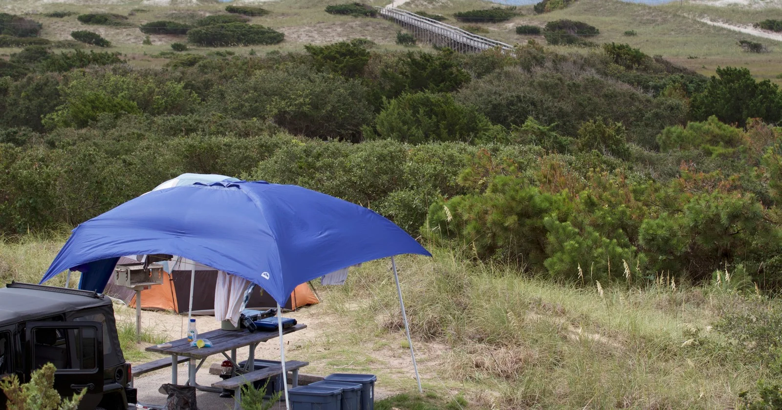 Archival National Park Service photograph of a campsite and boardwalk beyond the dunes at Frisco Campground