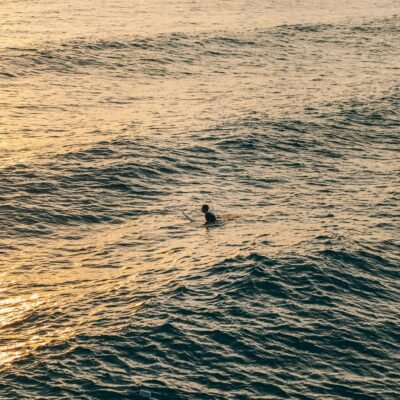 A surfer in the ocean at sunset