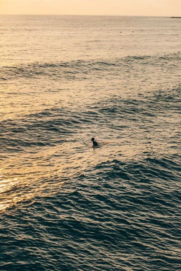 A surfer in the ocean at sunset