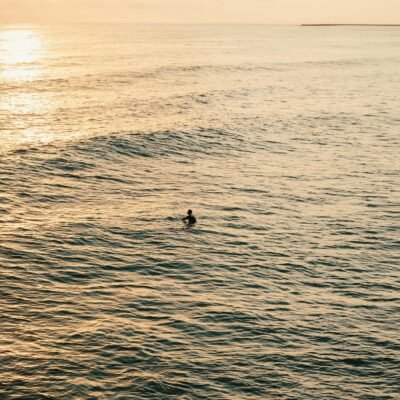 A surfer in the ocean at sunset