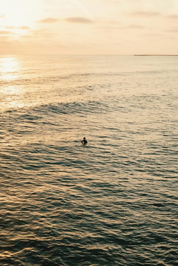 A surfer in the ocean at sunset