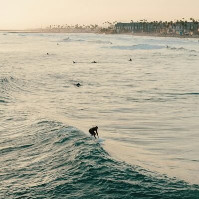 A surfer rides a wave at sunset