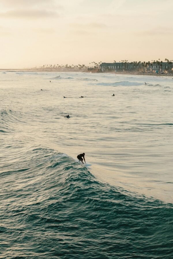 A surfer rides a wave at sunset